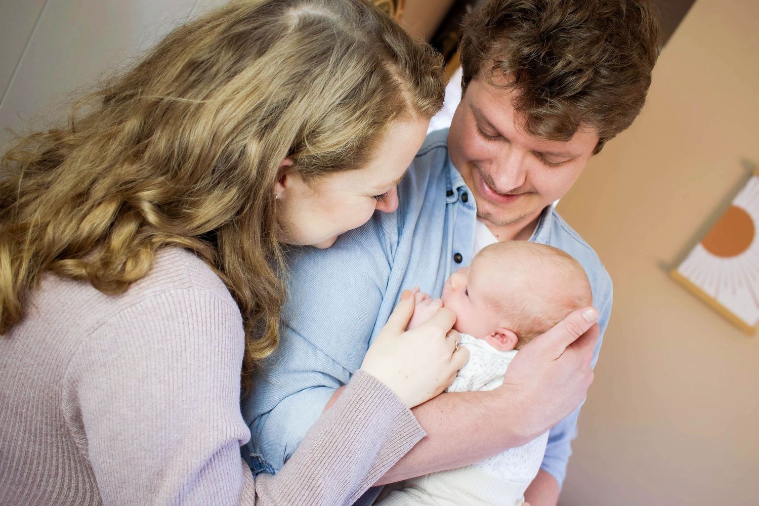 Intimate family moments captured in warm tones as parents bond with newborn.