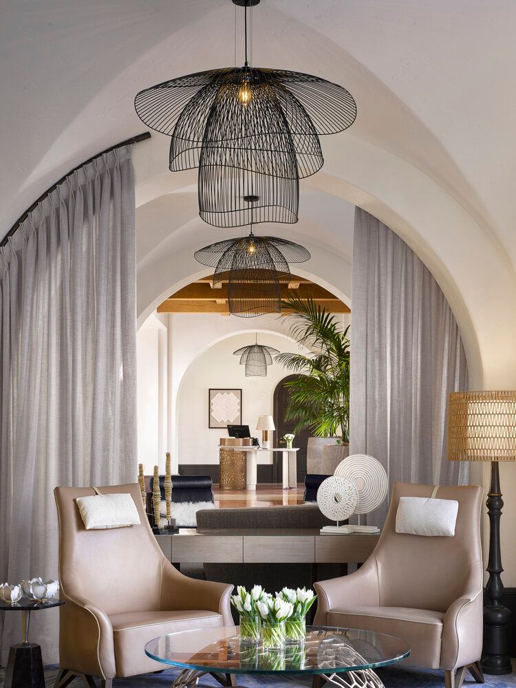Modern living room features stylish pendant lamps with rattan shades, arched doorways, and neutral-toned furniture.