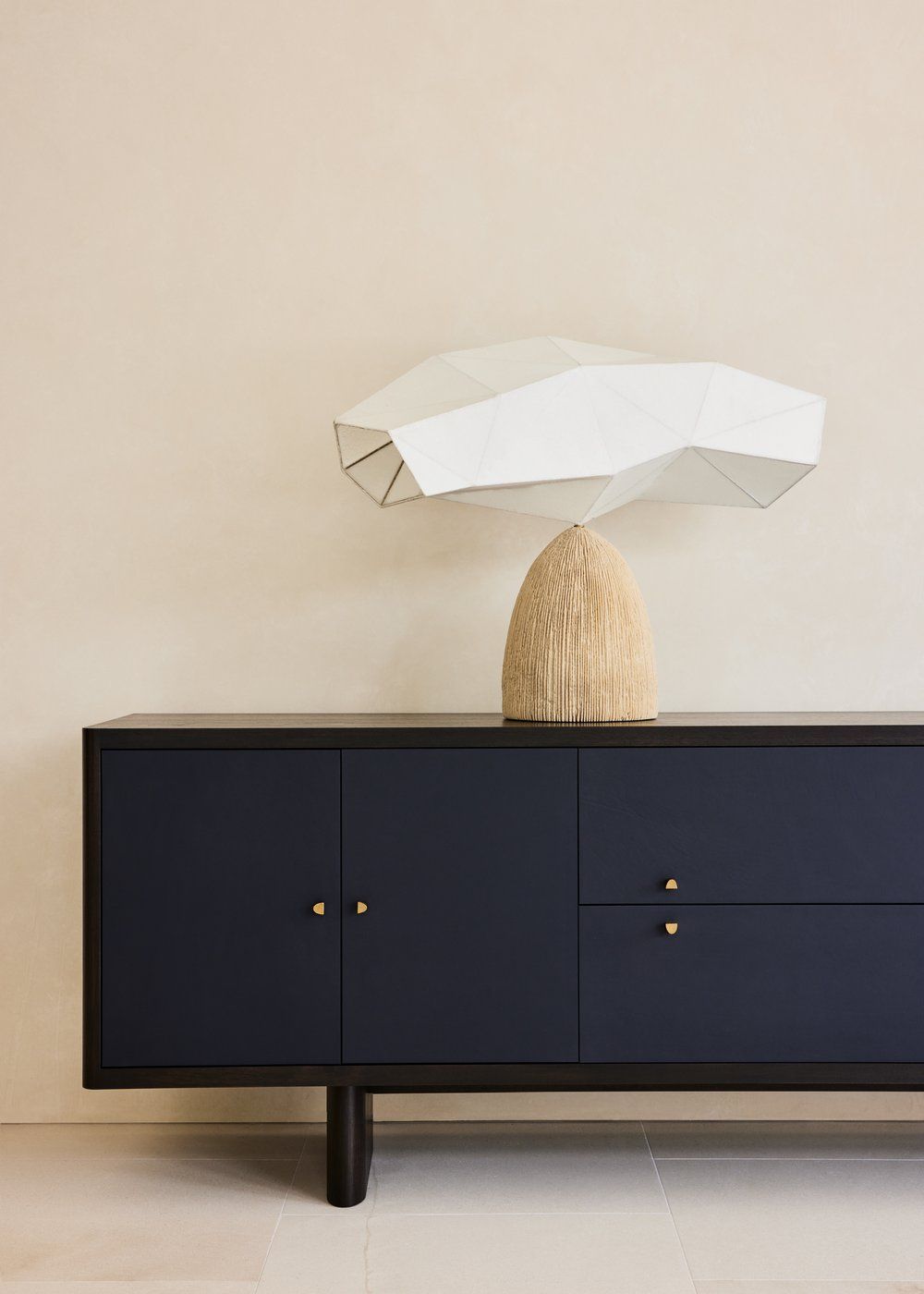 A sleek modern black media console with brass hardware and minimalist legs creates a striking low-profile silhouette.
