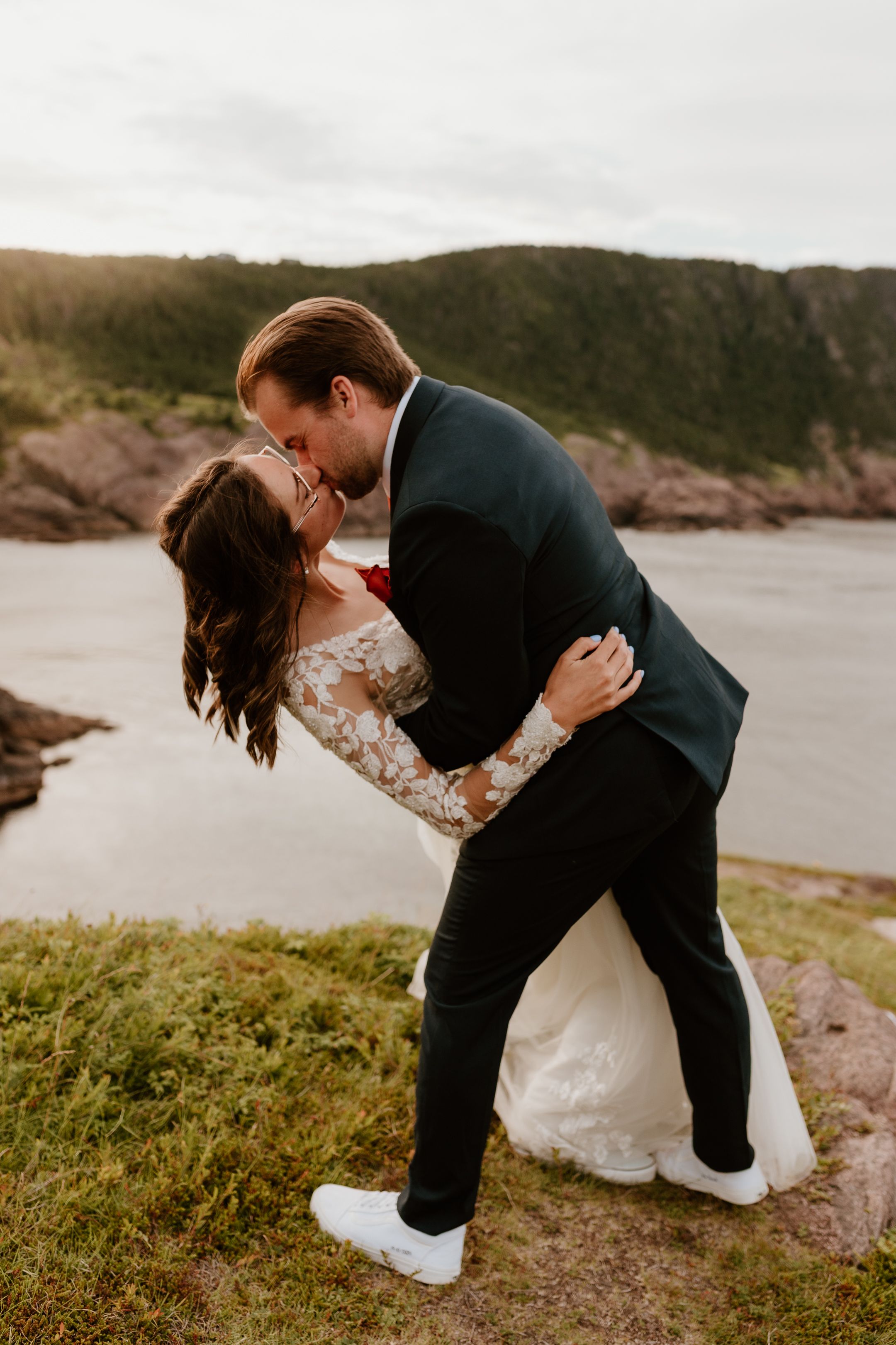 bride and groom kissing each other after reading their vows, groom is dipping bride, on a Newfoundland cliff