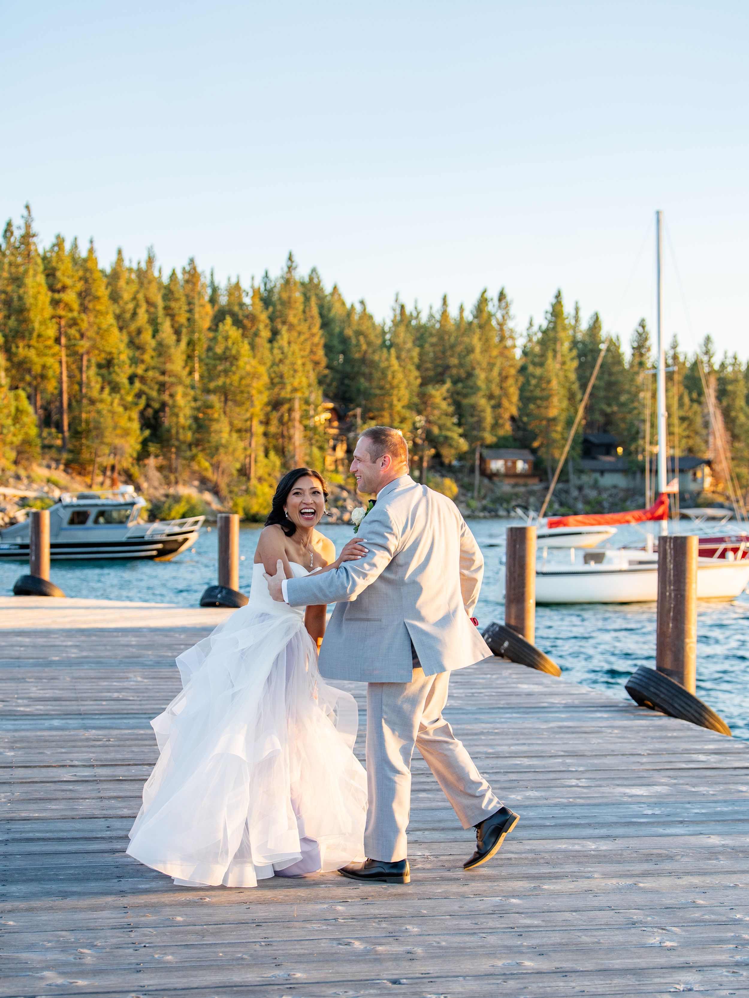 A couple shares a romantic sequence of dance moves on a wooden dock by a lake during golden hour.