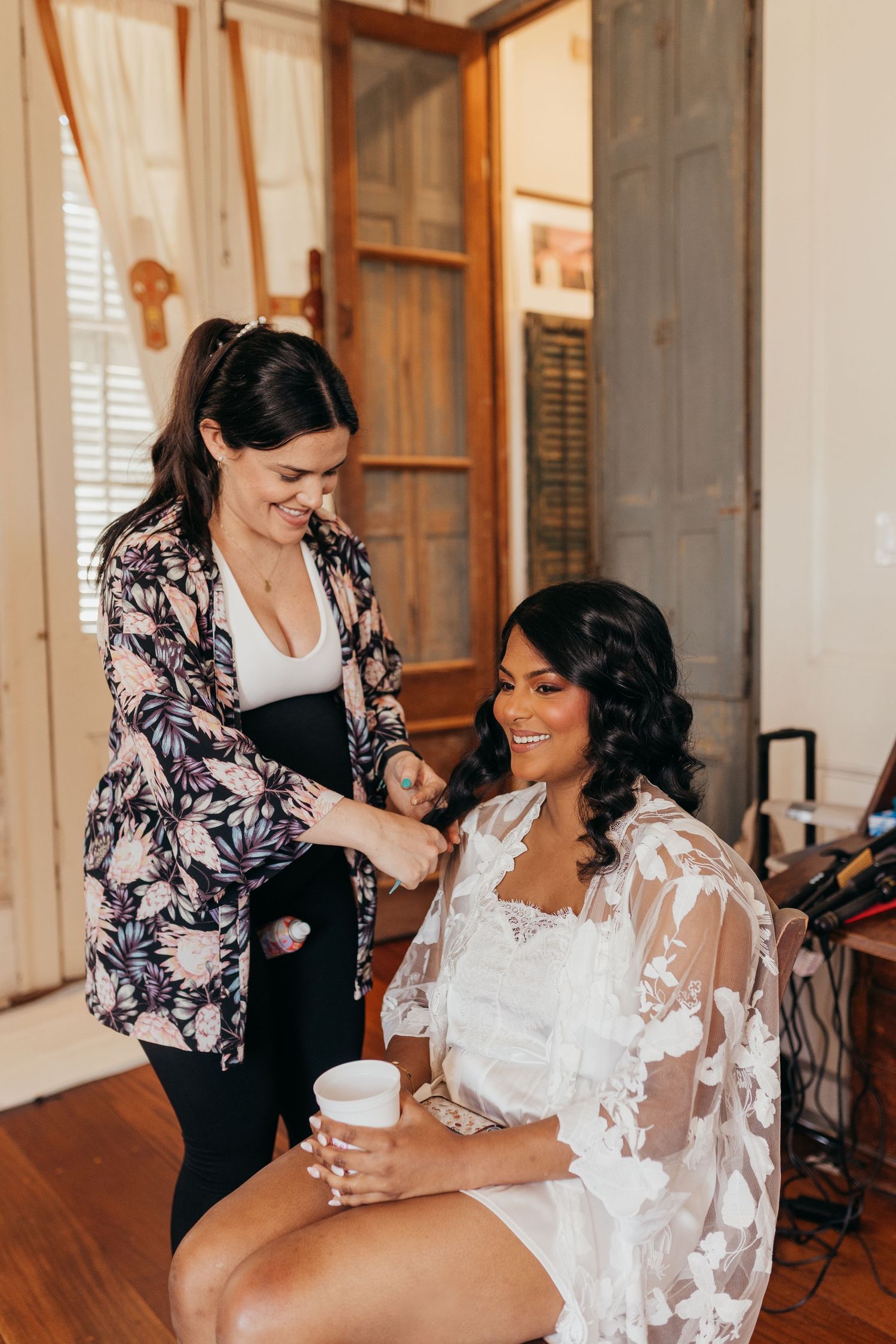 Makeup artist applies finishing touches to bride wearing delicate white lace robe during wedding preparations. at race and religious