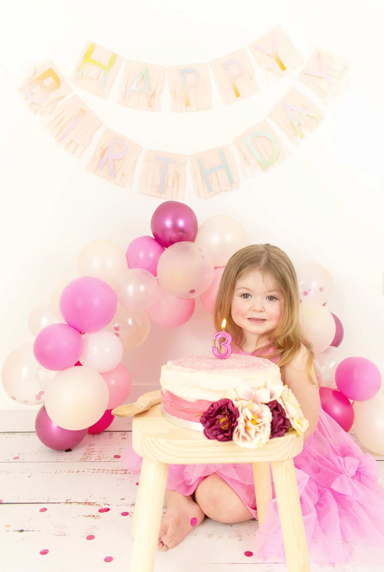 Birthday celebration setup with pink balloons and decorations for young child.