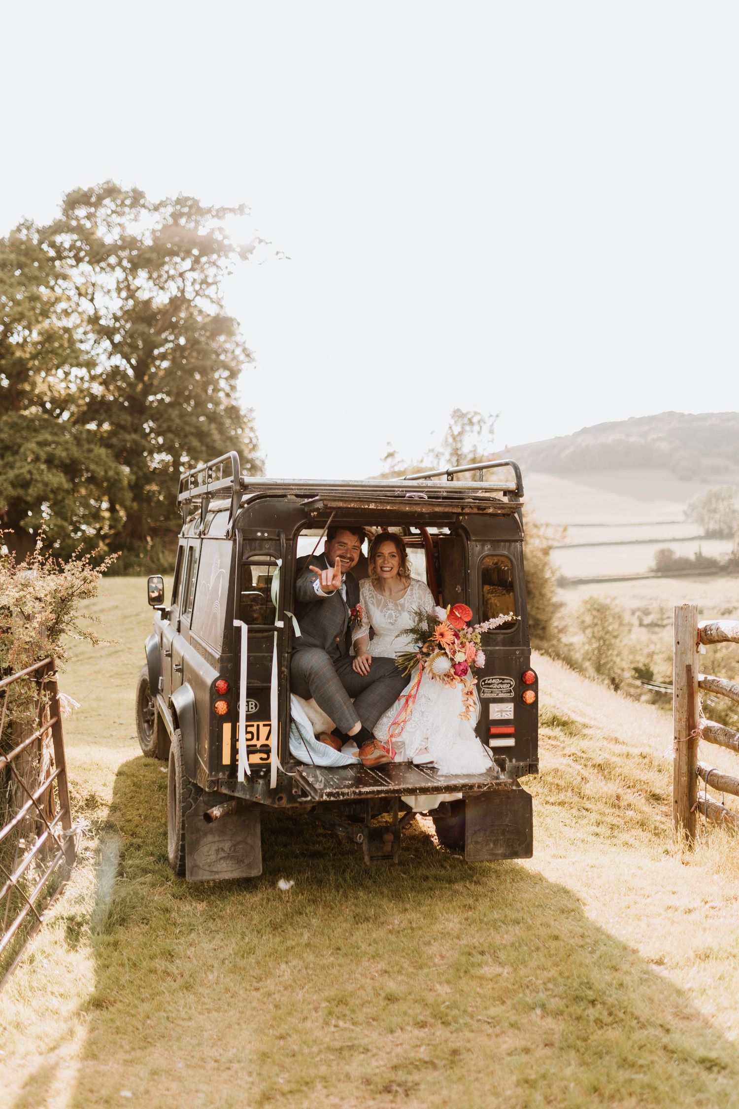 Four vintage-style photos showing a couple sitting together in a dark-colored Land Rover Defender parked on a grassy hillside.