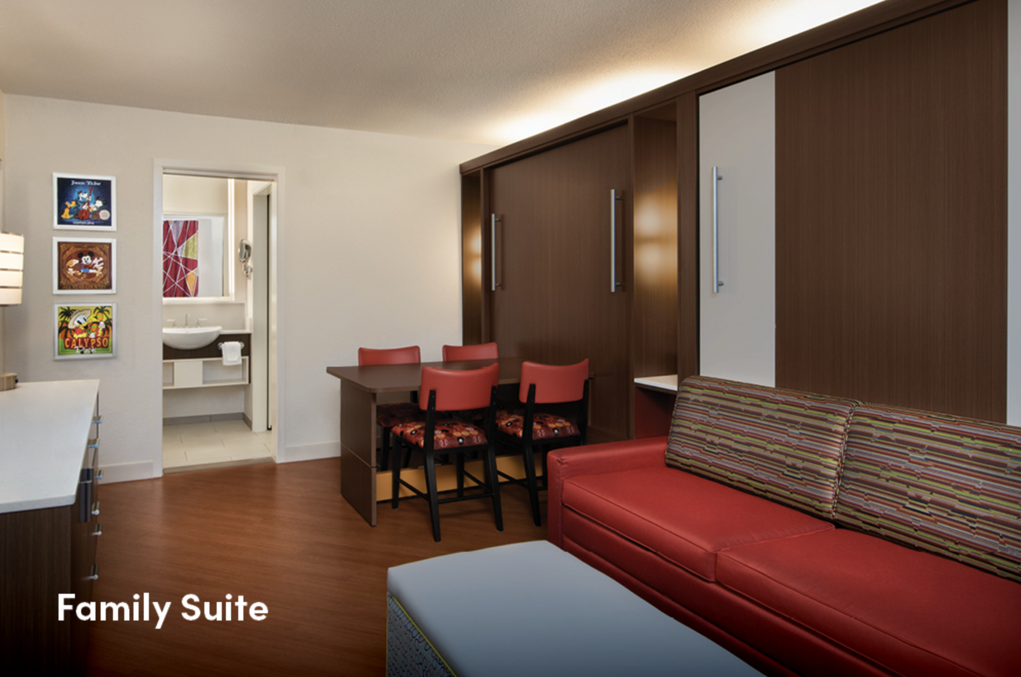 Family suite living area with red sofa, dining table, and contemporary decor.