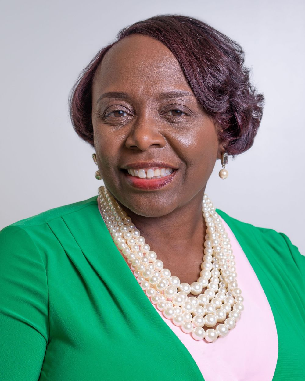 Headshot of middle-aged black woman in green and pink blouses, taken by Brian Balloon Photography