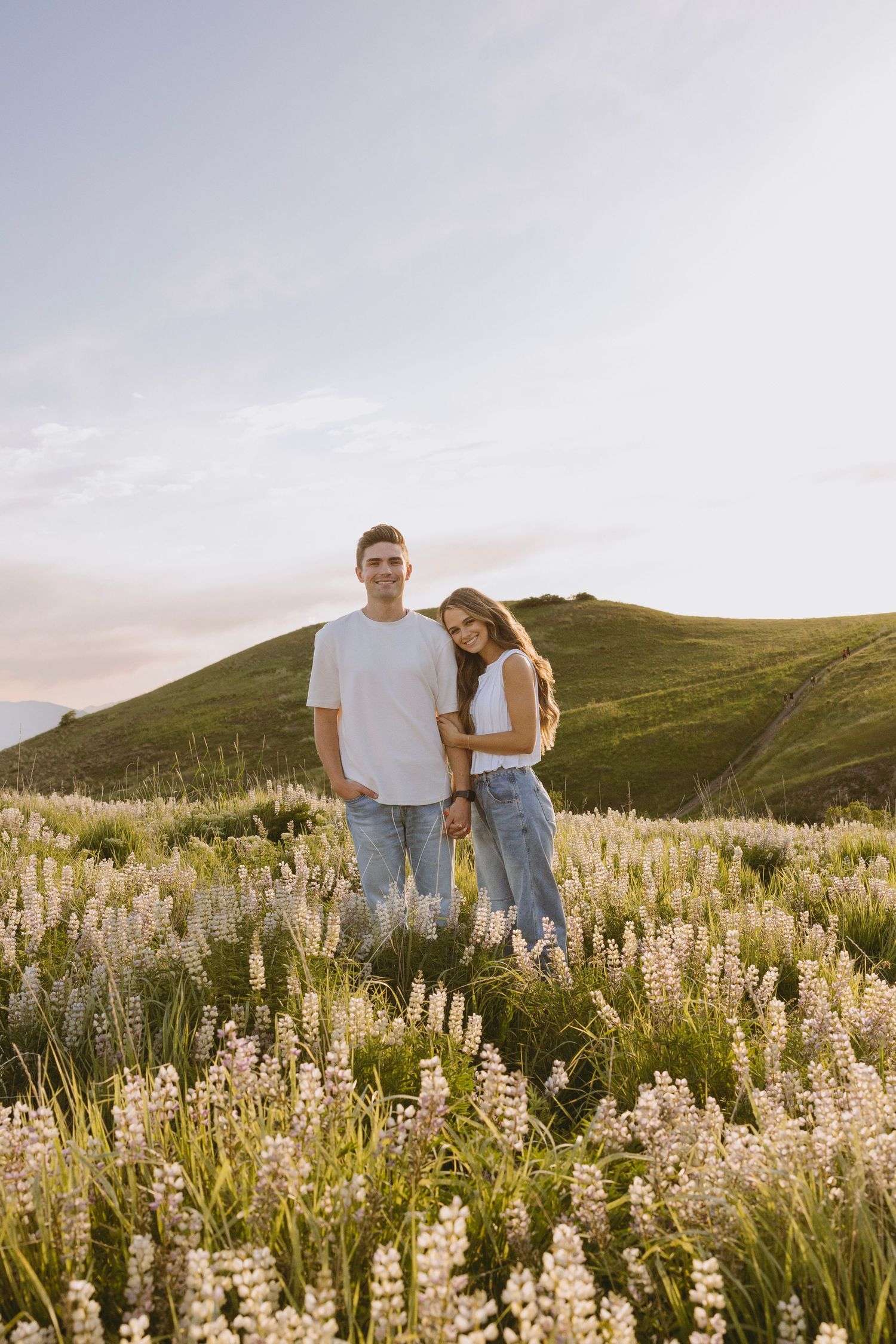 A couple shares an intimate moment at the edge of a scenic canyon with red rock formations stretching to the horizon.