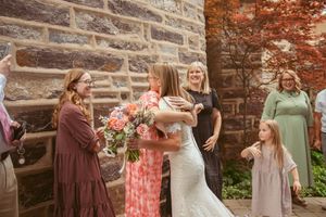 Group celebrates together outside historic stone building with floral arrangements and festive attire.