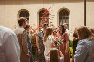 Guests mingle and enjoy refreshments at an outdoor wedding reception under a covered pavilion.