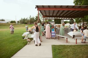 A group of people gathered at an outdoor park shelter during a community event on a sunny summer day.