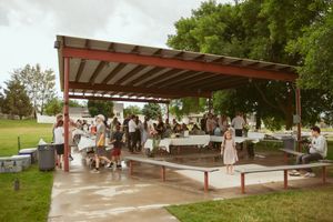 Two individuals dancing together under a covered outdoor pavilion at what appears to be a summer celebration.