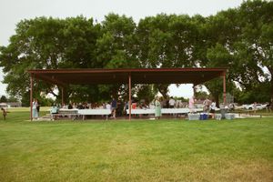 Wide view of an outdoor pavilion area with trees and grass surrounding the gathering space.