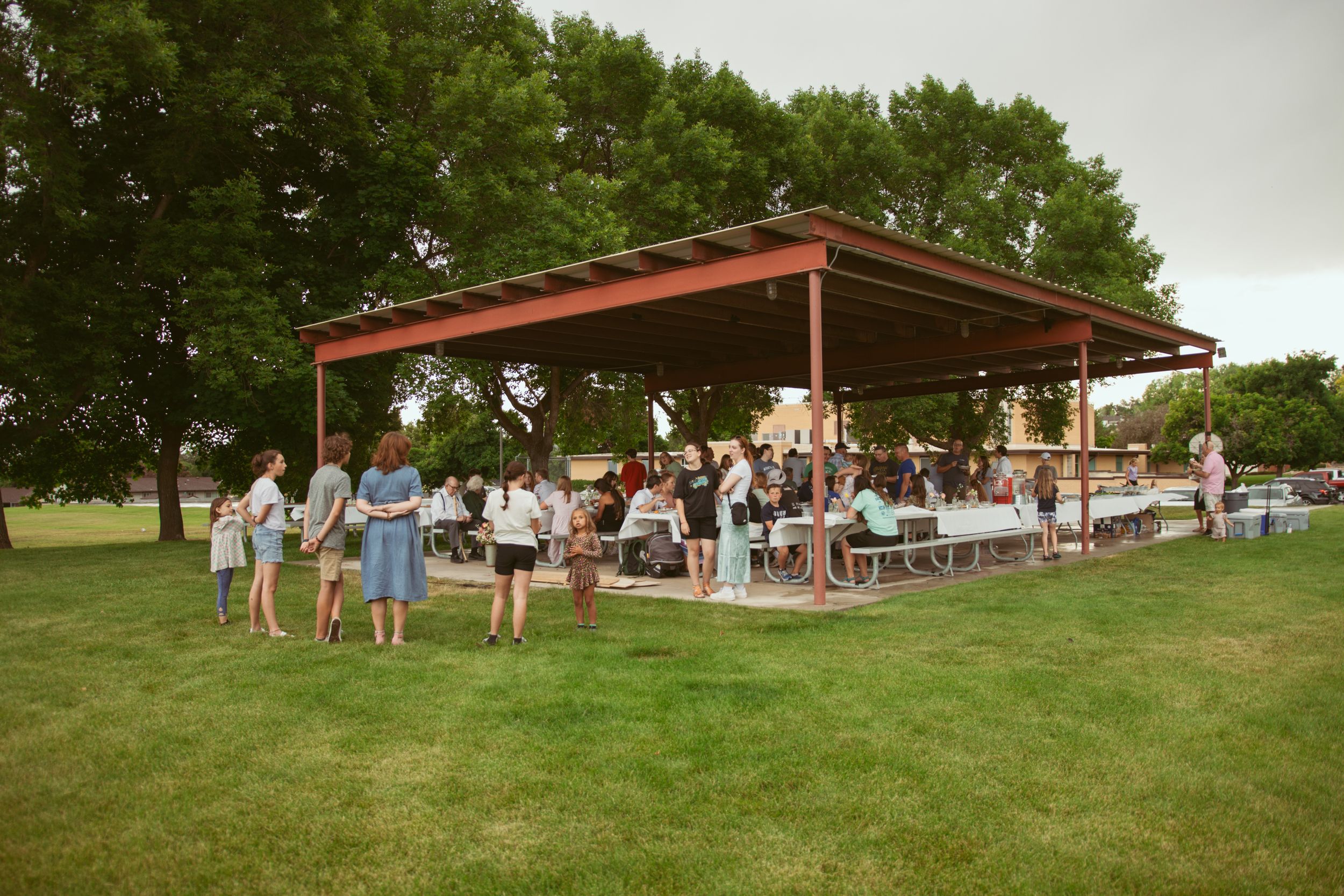 A panoramic view of a wedding reception venue with a red-roofed pavilion surrounded by green lawn and trees.