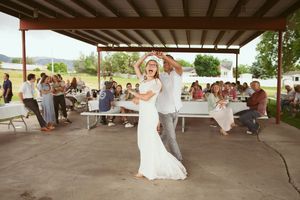 Dancers share a romantic moment under a covered patio during a sunny outdoor celebration with guests seated nearby.
