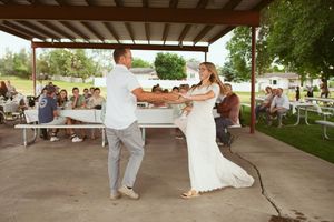 Multiple couples dance together under a covered outdoor pavilion during what appears to be a festive celebration.