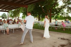 Dancing under a covered pavilion during an outdoor summer wedding reception celebration.