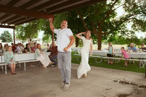 A joyful celebration dance takes place under a covered outdoor space with guests watching.