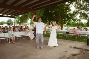 Celebration with dancing and entertainment at an outdoor wedding reception under a covered pavilion.