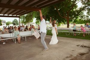 An outdoor wedding ceremony setup under a rustic wooden pavilion surrounded by lush greenery and trees.