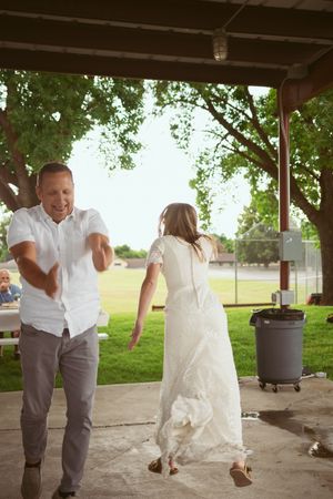 A couple dances energetically under a covered patio space at an outdoor celebration.