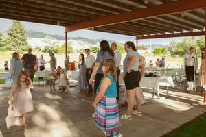 People gather under a covered outdoor patio area during a daytime event.