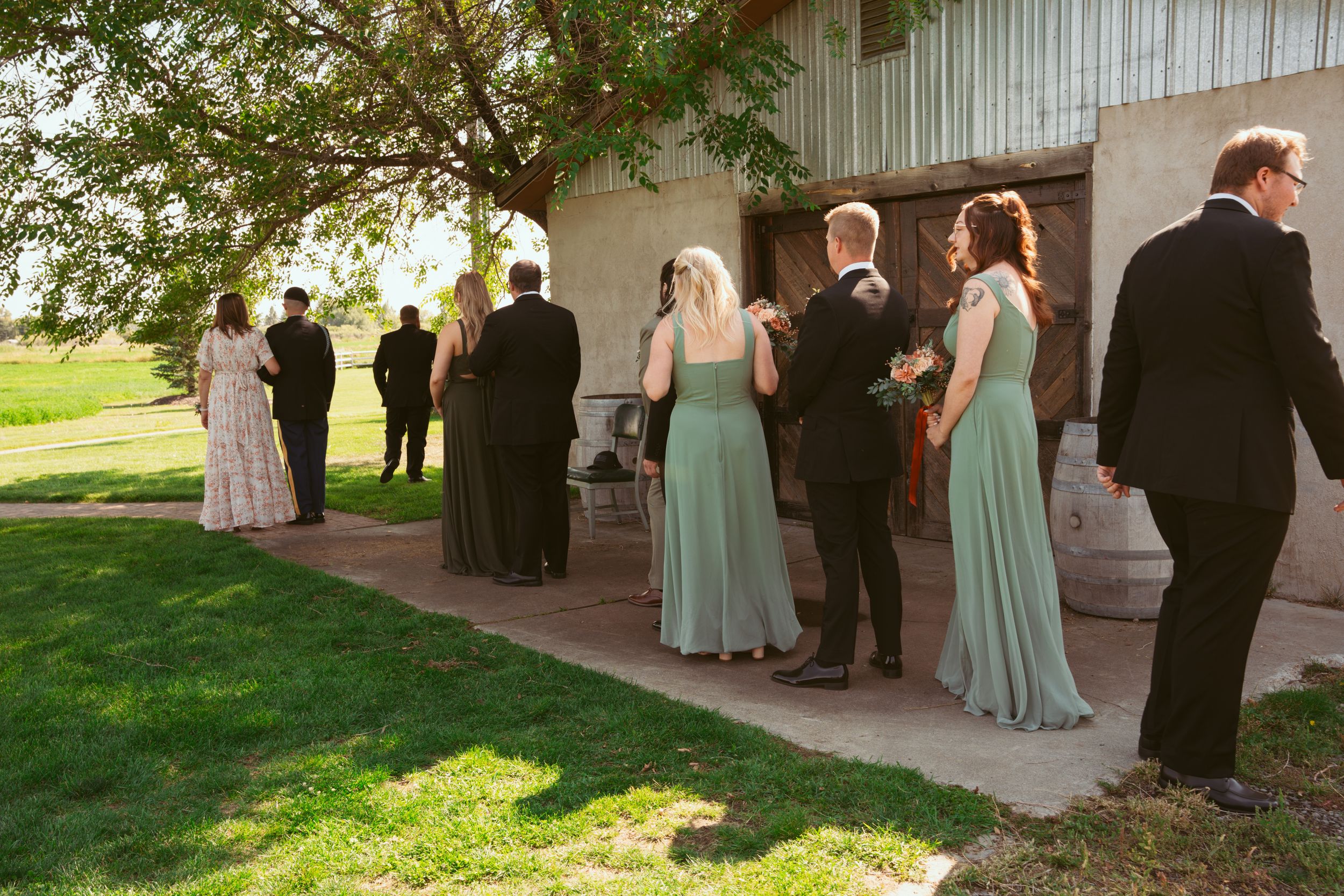 Wedding party members stand in a line outside a venue wearing formal attire in mint green and black.