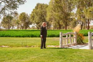 Wedding guests seated outdoors on white chairs surrounded by trees at a nature-inspired ceremony.
