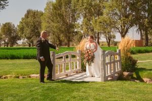 Couple stands on decorative white bridge during outdoor wedding ceremony.