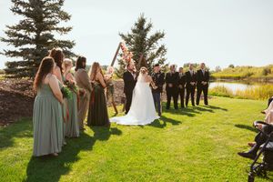 Wedding attendees gathering on a grassy lawn during an outdoor ceremony with evergreen trees in the background.