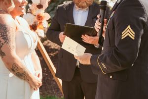 Close-up of wedding ceremony details with wooden arch and peach floral decorations.