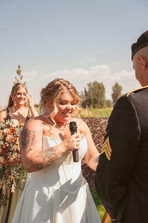 Wedding party laughs joyfully during an outdoor ceremony in a scenic natural setting.