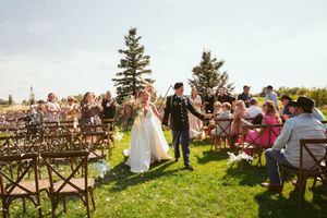 Guests seated in wooden chairs at an outdoor wedding ceremony overlooking a scenic mountain landscape.