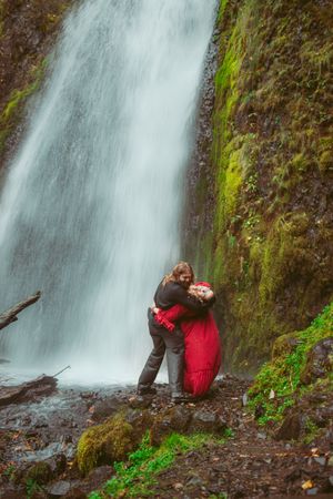 A misty waterfall cascades down a moss-covered cliff face surrounded by lush green vegetation in the Pacific Northwest.