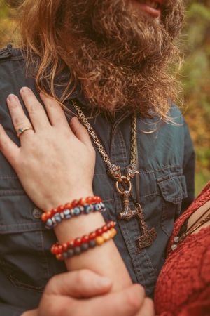 Close-up series of hands wearing blue denim and burgundy clothing with beaded bracelets and a pendant necklace.