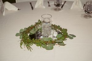 Elegant table centerpiece featuring greenery and eucalyptus leaves around a glass votive holder.