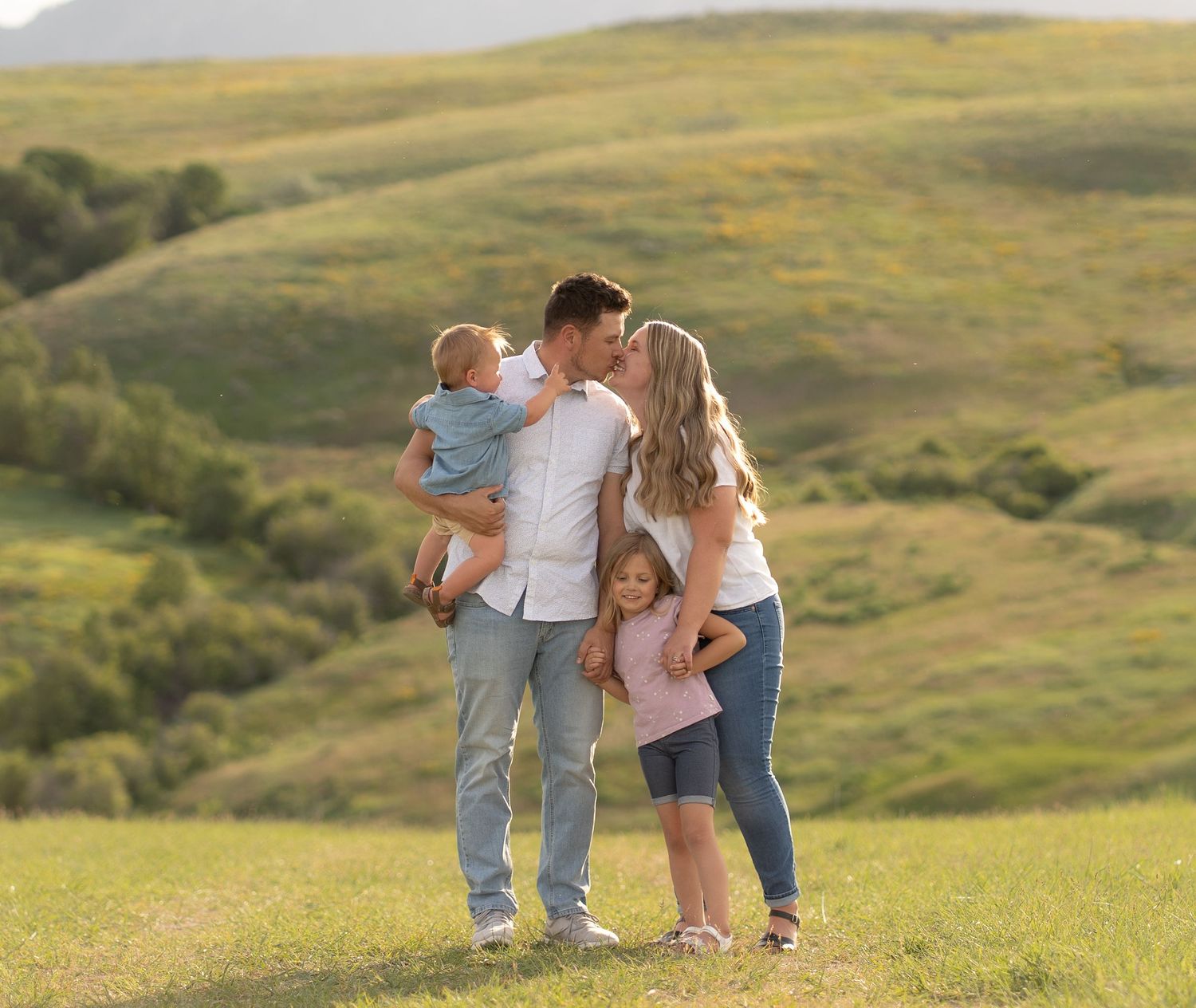 Family embracing in scenic Logan, Utah hills during a family photography session with their local family photographer in Cache Valley.