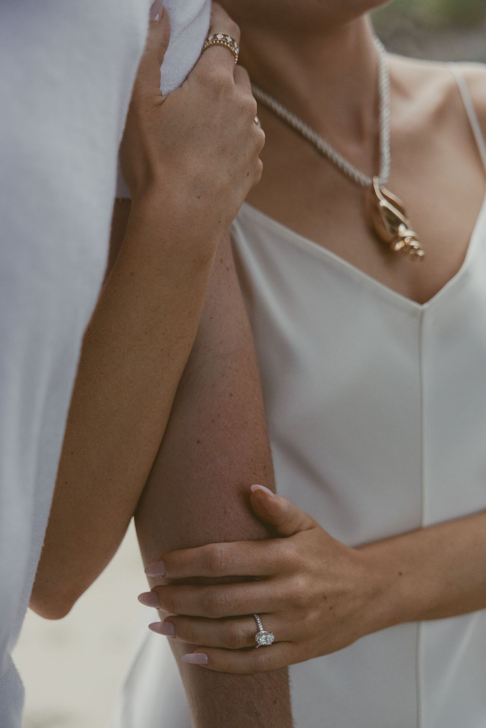 Close-up of engagement ring and delicate necklace on bride.