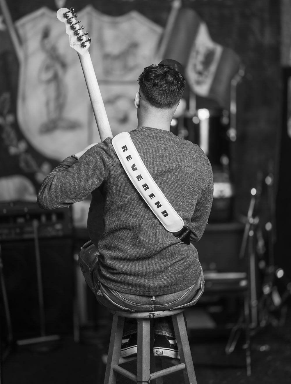 Black and white photo of musician performing with guitar on stage.