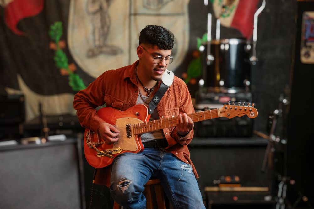 Musician playing acoustic guitar during live performance on stage.