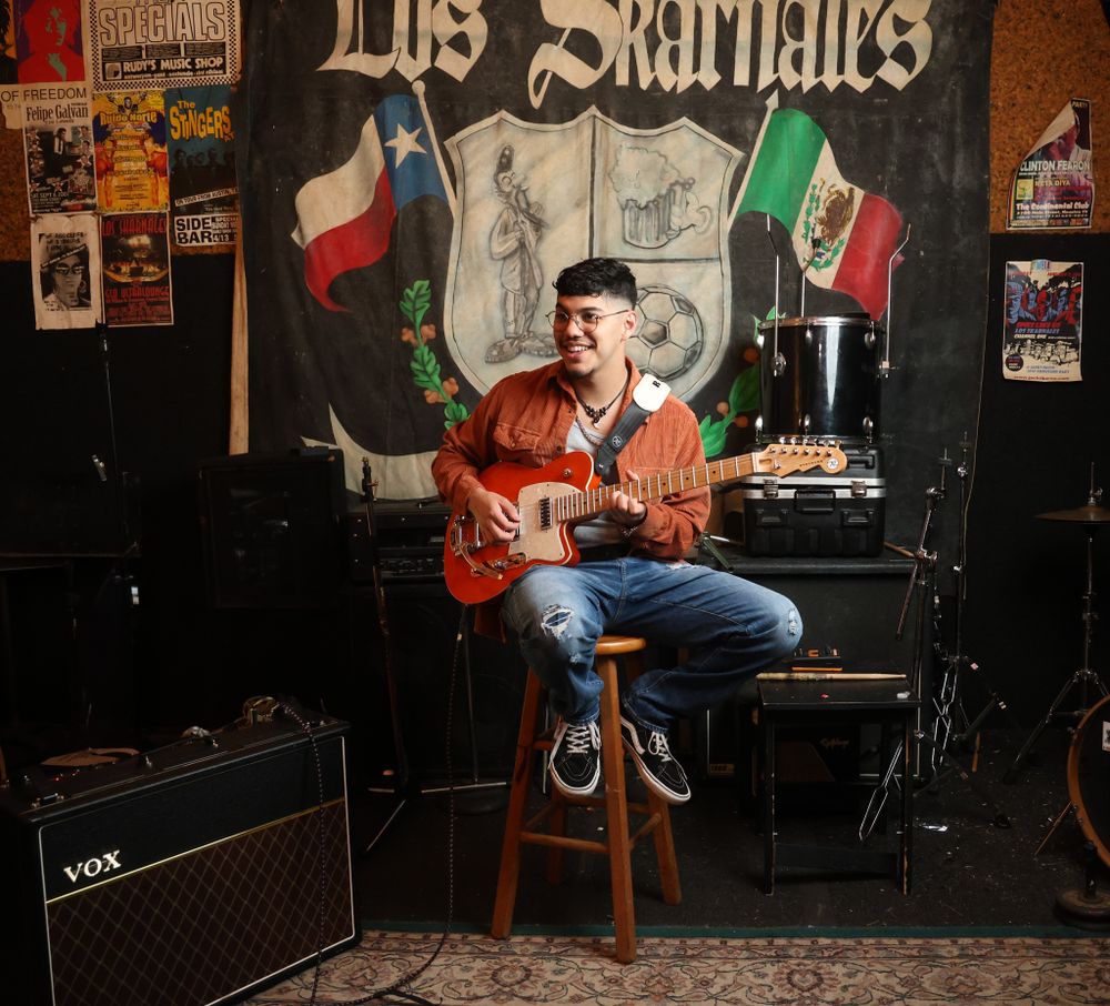 Energetic performance shot in front of Los Skarnales mural with Mexican and Texas flags.