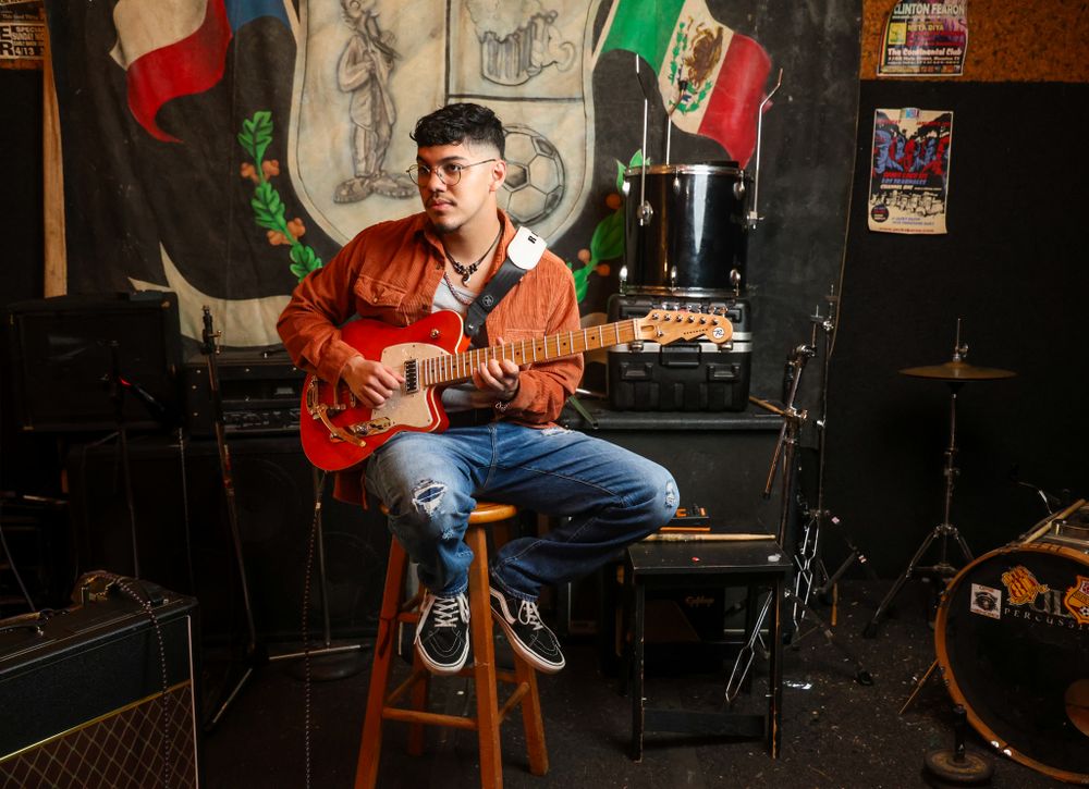 Guitar player performs in front of Los Skarnales logo and Mexican flags on stage.