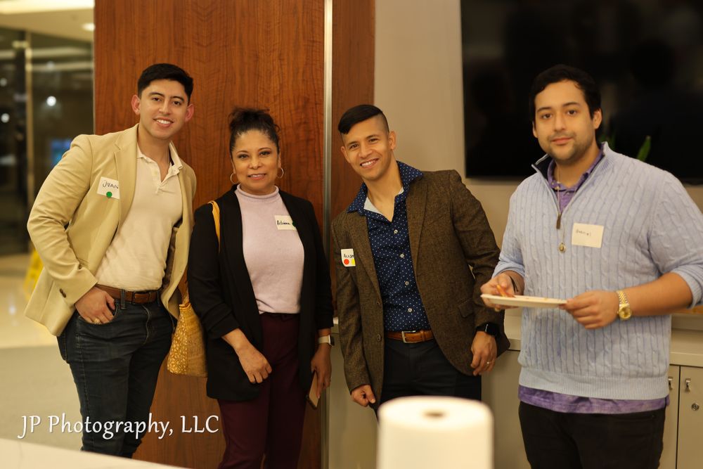 Four professionally dressed attendees posing together at a networking event.