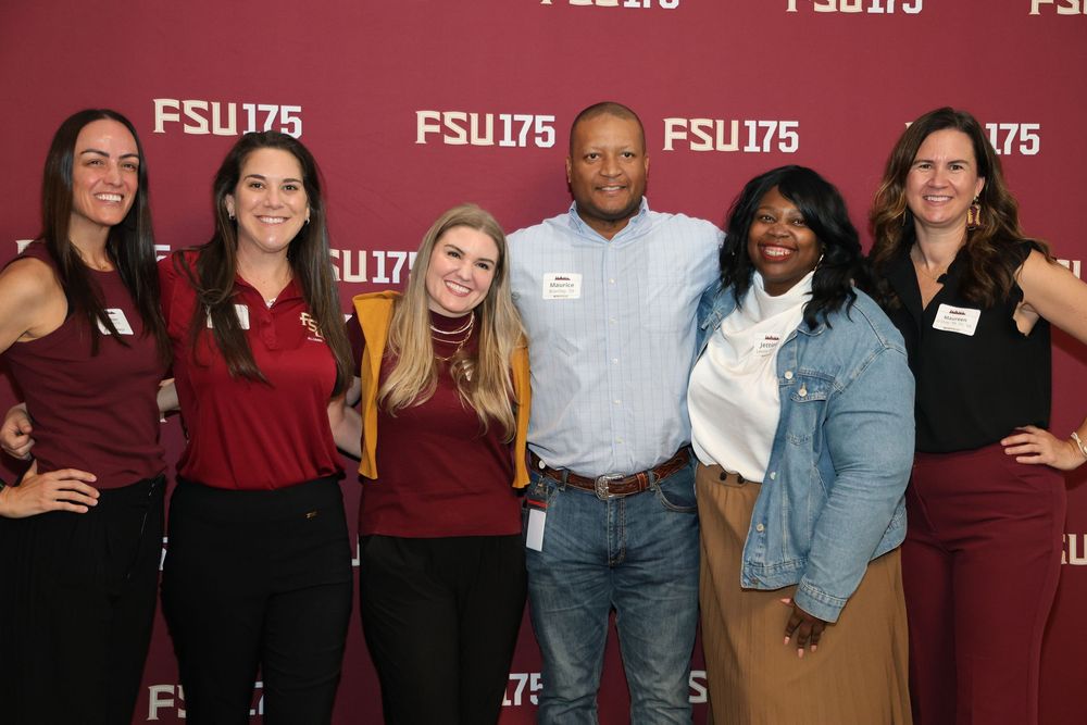 Six people smiling together in front of an FSU175 anniversary backdrop at a Florida State University event.