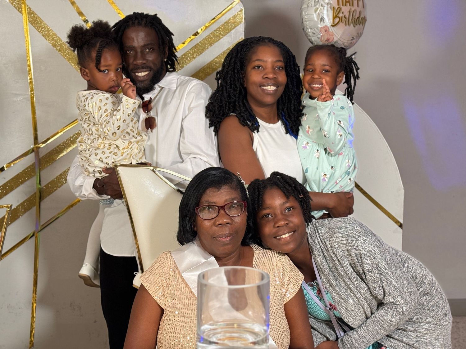 A joyful family gathering with people dressed in white and gold posing together.