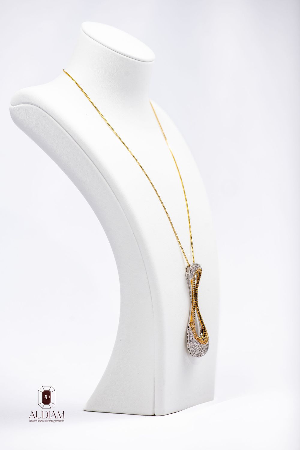 Delicate gold teardrop pendant necklace with diamond accents displayed on white jewelry bust.