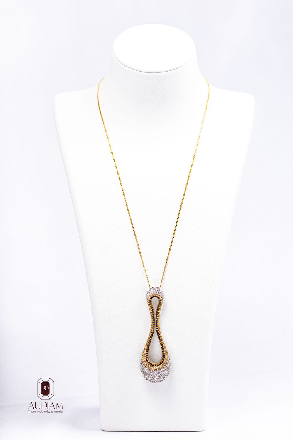 Elegant twisted teardrop pendant necklace with diamonds on white gold chain displayed on white jewelry bust.