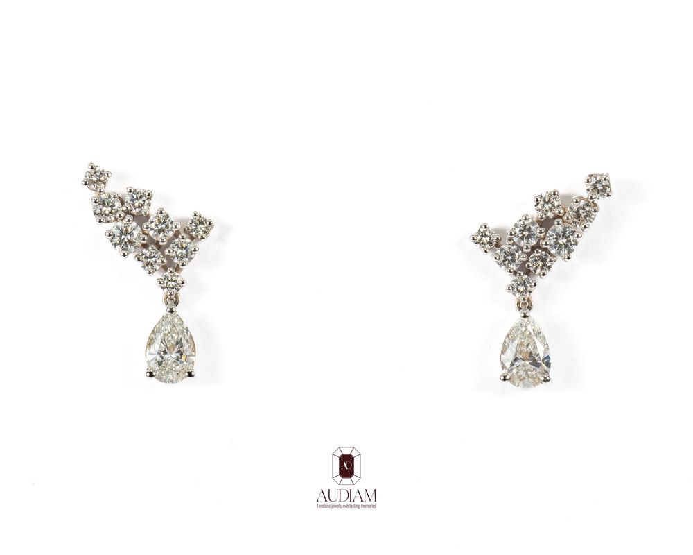 Elegant white gold drop earrings featuring pear-shaped diamonds and pavé crystal accents in a delicate curved design.