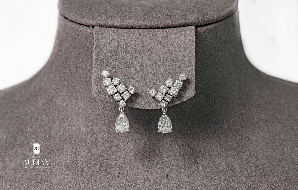Luxury rhinestone or crystal chandelier drop earrings displayed on dark grey stand.