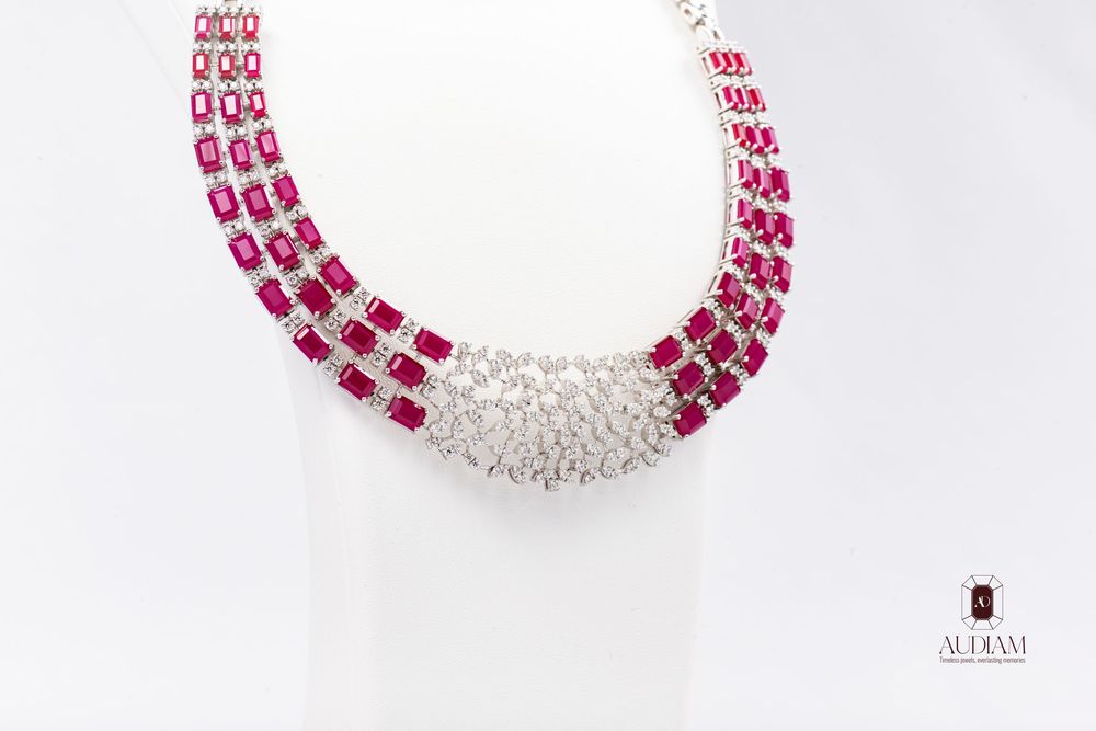 Elegant ruby and diamond choker necklace featuring three strands of pink gemstones with a white crystal centerpiece.
