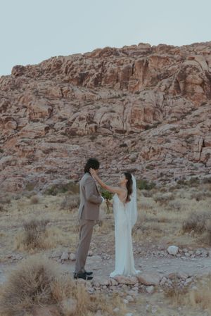 A bride and groom are standing face to face of each other in red rock canyon in Las Vegas.